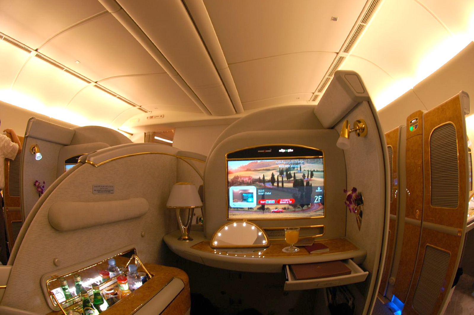 Suíte privativa de primeira classe com poltrona, minibar e tela individual