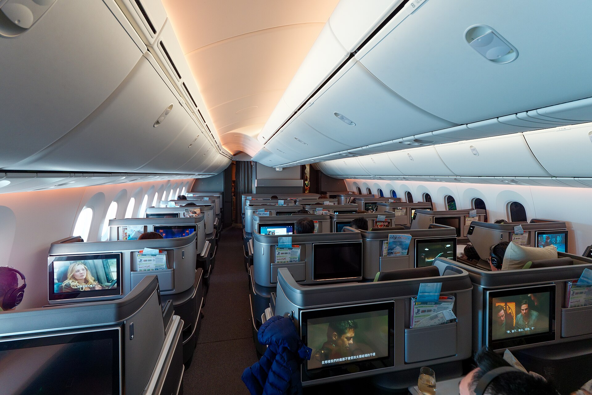 Cabine executiva de Boeing 787 com assentos individuais e telas de entretenimento